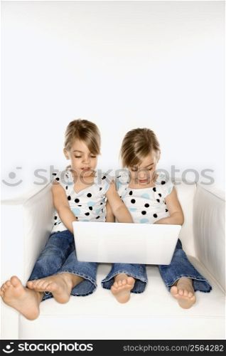 Female children Caucasian twins playing with laptop computer.