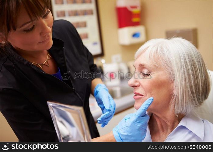Female Client Looking In Mirror After Botox Treatment