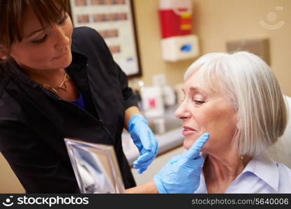 Female Client Looking In Mirror After Botox Treatment