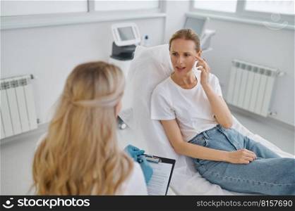 Female client showing with fingers at wrinkles talking to young doctor cosmetologist. Consultation before hardware ultrasound procedure in modern office. Female client showing with fingers at wrinkles talking to cosmetologist