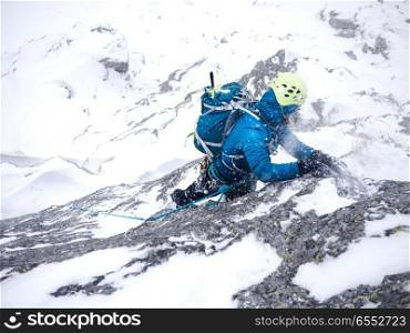 Female climber in the storm during an extreme winter climb. West italian Alps, Europe.
