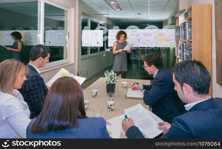 Female coach talking while looking project management to business team sitting at table in headquarters. Female coach looking project management in business team training