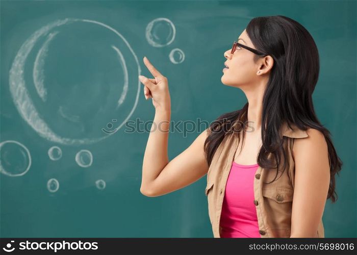 Female college student pointing at blackboard