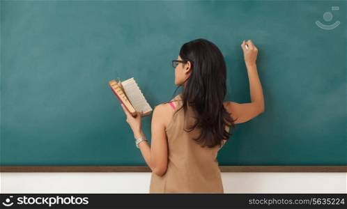 Female college student writing on blackboard