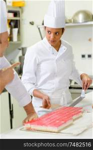 female confectionery apprentice slicing a cake