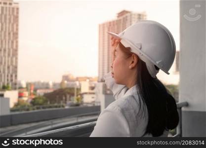 Female construction engineer with a tablet computer at a construction site. Confident woman architect in white helmet looking at a construction site. Construction and architecture concept.