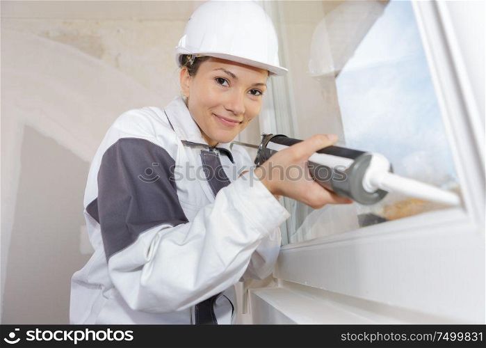 female construction worker holding caulking gun and smiling