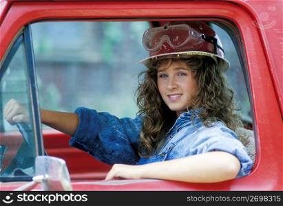 Female construction worker in hard-hat driving truck