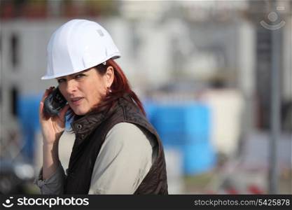 Female construction worker on site with a phone