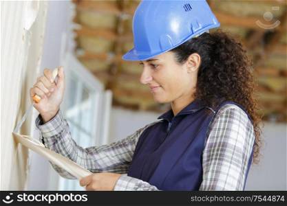 female construction worker removing wallpaper with a scraper