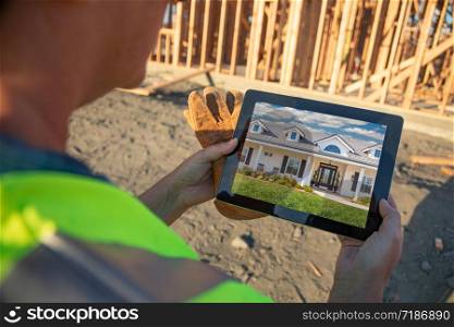 Female Construction Worker Reviewing House Photo on Computer Pad at Construction Site.