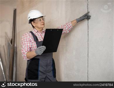 female construction worker with helmet inspecting with clipboard