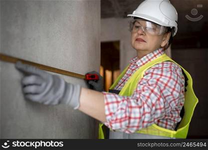 female construction worker with helmet tape measurer