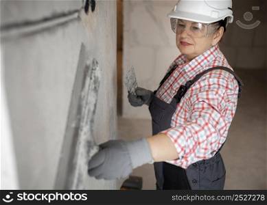 female construction worker with helmet working wall