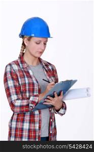 Female construction worker writing on clip-board