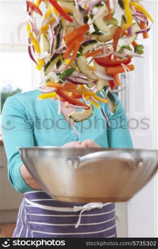 Female Cook Tossing Vegetables In Pan Obscuring Her Face