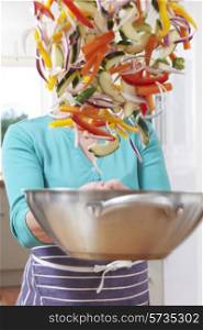 Female Cook Tossing Vegetables In Pan Obscuring Her Face