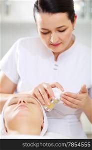 Female cosmetician is going to apply facial cosmetic during the procedure in the beauty treatment salon