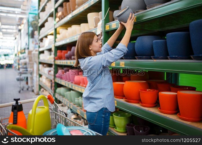 Female customer at the shelf with pots, shop for gardening. Woman buying equipment in store for floriculture, florist instrument purchasing