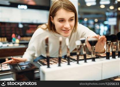 Female customer choosing brushes in the makeup shop. Cosmetics choosing in beauty store, make-up. Female customer choosing brushes in makeup shop