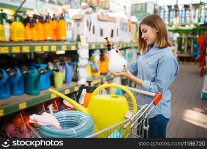 Female customer choosing gardening tools in shop for gardeners. Woman buying equipment in store for floriculture, florist instrument purchasing