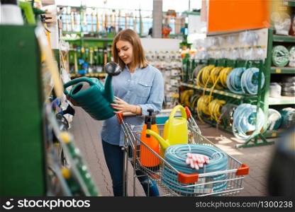 Female customer choosing gardening tools in shop for gardeners. Woman buying equipment in store for floriculture, florist instrument purchasing. Female customer choosing tools, shop for gardeners
