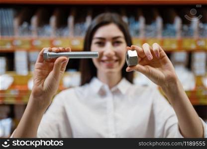 Female customer choosing nuts and bolts in hardware store. Buyer look at the goods in diy shop, shopping in building supermarket