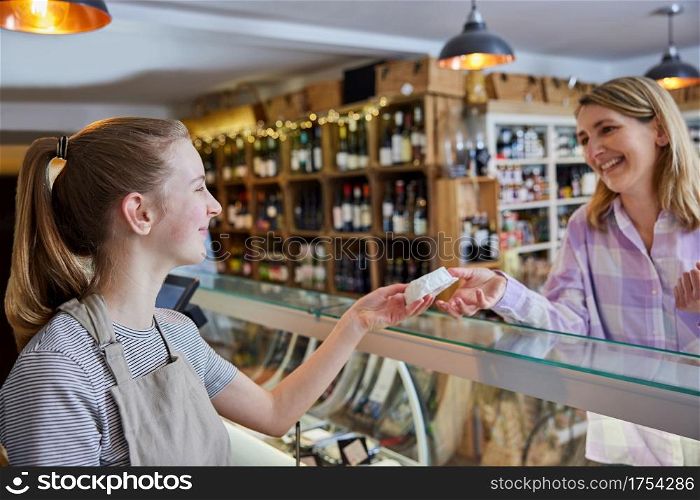 Female Customer Delicatessen Food Store Buying Local Cheese From Teenage Sales Assistant