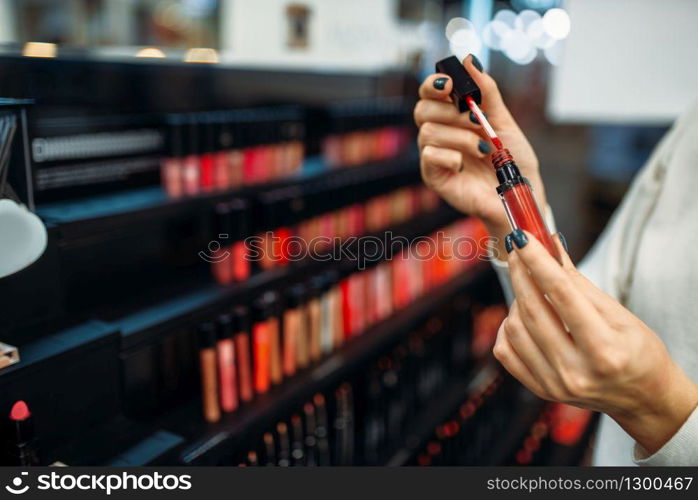 Female customer holds eyeshadows in the make-up shop. Cosmetics choosing in beauty store, makeup salon