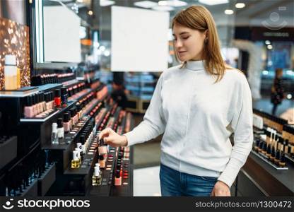 Female customer looking cosmetics in the makeup shop. Nail varnish choosing in beauty store, make-up salon