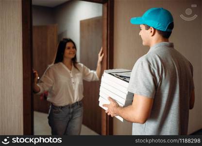 Female customer on the doorstep and pizza delivery boy, delivering service. Deliver from pizzeria and woman indoors