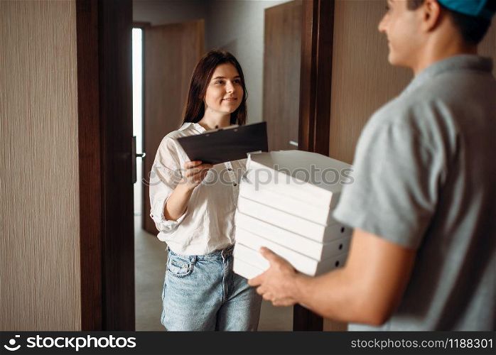 Female customer takes order from pizza delivery boy, fast delivering service. Courier from pizzeria carrying carton boxes and woman at the door