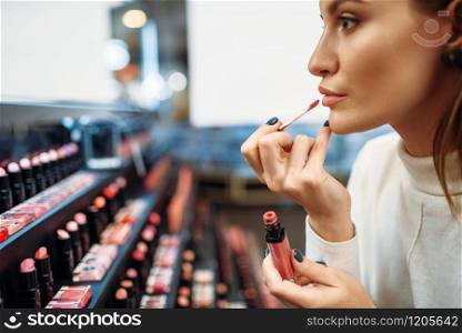 Female customer testing lip liner in the make-up shop. Cosmetics choosing in beauty store, woman in makeup salon. Female customer testing lip liner in make-up shop
