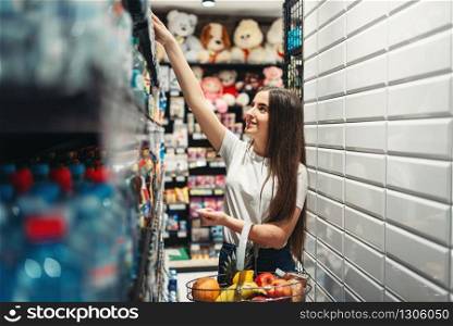 Female customer with cart in food store. Woman shopping in grocery, buyer in market. Female customer with cart in food store