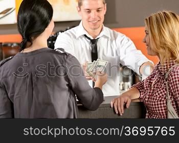 Female customers paying by cash dollar in bar to bartender