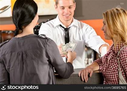 Female customers paying by cash dollar in bar to bartender