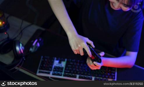 Female cyber hacker gamer playing or streaming video games on computer with joystick in neon light.