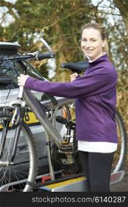 Female Cyclist Taking Mountain Bike From Rack On Car