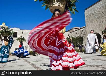 Female dancers dancing with potted plant over their head, Oaxaca, Oxaca State, Mexico