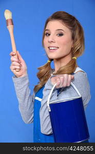 Female decorator holding tin of paint and brush