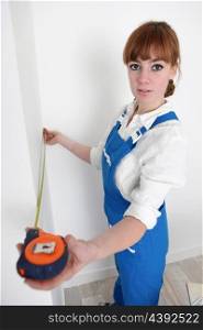 Female decorator measuring a wall