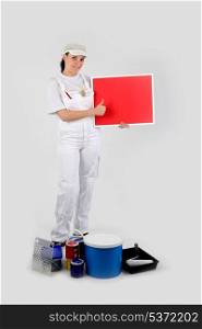 Female decorator stood with red poster