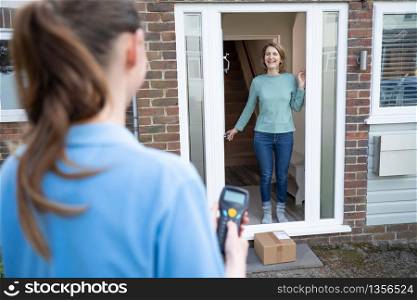 Female Delivery Driver Leaving Package Outside House For Safety Observing Social Distancing During Coronavirus Pandemic