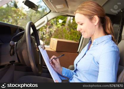 Female Delivery Driver Sitting In Van Filling Out Paperwork