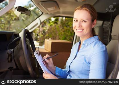Female Delivery Driver Sitting In Van Filling Out Paperwork