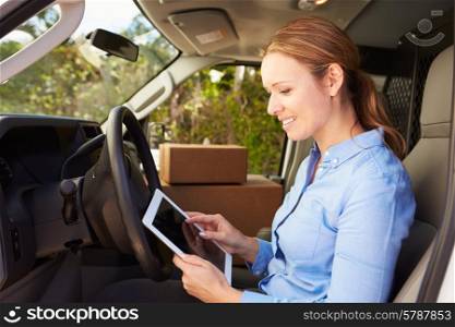 Female Delivery Driver Sitting In Van Using Digital Tablet