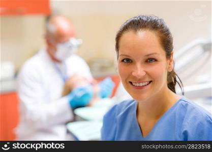 Female dental assistant smiling at stomatology office dentist with patient