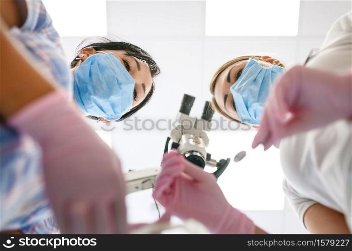 Female dentist and assistant, view from patient mouth, stomatology. Doctor in uniform, medical worker, medicine and health, professional teeth care, dentistry. Dentist and assistant, view from patient mouth
