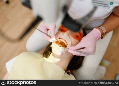 Female dentist and patient with opened mouth in clinic, top view, stomatology. Doctor in uniform, medical worker, medicine and health, professional teeth care, dentistry. Female dentist and patient with opened mouth