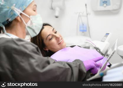 Female dentist pointing at patient’s X-ray image in dental office. High quality photo. Female dentist pointing at patient’s X-ray image in dental office.